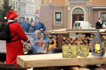 Święty Mikołaj grzeje dłonie przy ognisku na rynku w Opolu. - obrazy, fototapety, plakaty
