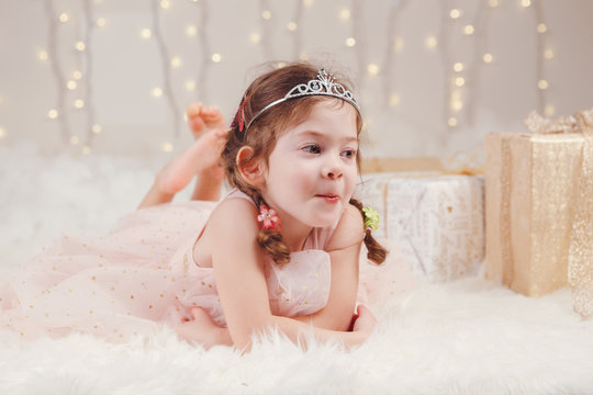 Portrait of white Caucasian girl wearing princess diadem crown celebrating Christmas or New Year. Little adorable cute child in studio with winter holiday decoration