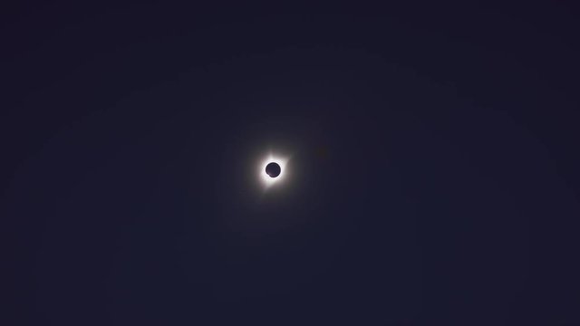Distant bright lens flare changing to reveal total solar eclipse / Driggs, Idaho, United States