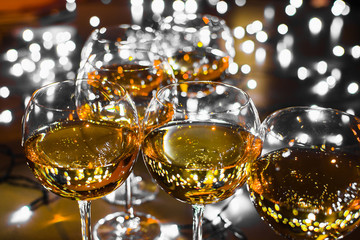 Glass glasses with wine on the background of luminous garlands. Good New Year spirit. Multicolored bokeh