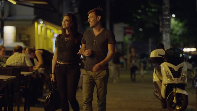 Medium shot of couple walking at night and entering restaurant / Berlin, Germany