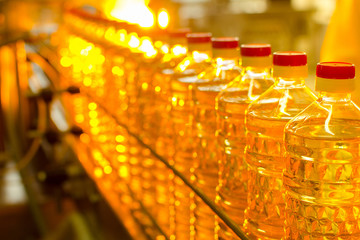 Fototapeta na wymiar Oil in bottles. Industrial production of sunflower oil. Conveyor line for bottling and packing. Sunflower oil plant.