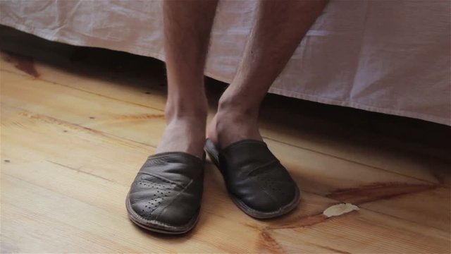 slippers are torn,A man gets up at bed and wears torn slippers