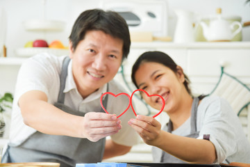 Asian couple holding red hearts.
