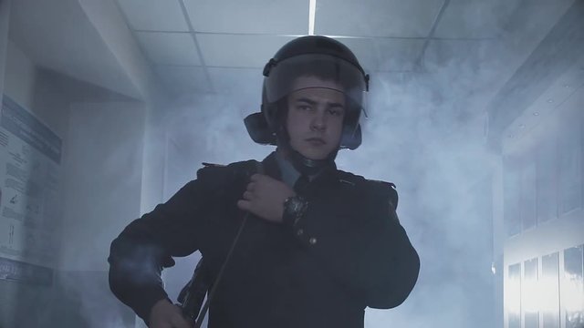 A policeman in a section in smoke and with a gun