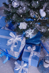 Christmas gifts under the tree. New Year cosy home interior. Snowfall, snow effect