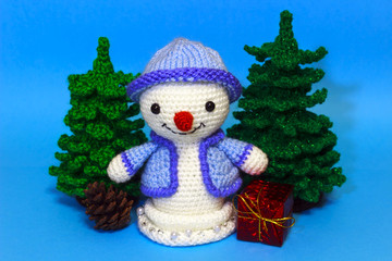 snowmen next to a Christmas tree among toys on a blue background