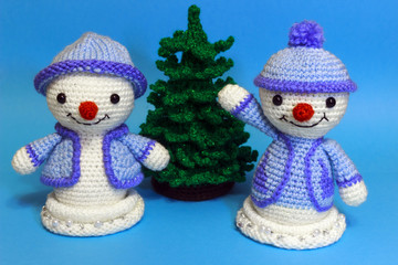 two snowmen next to a tree but a blue background