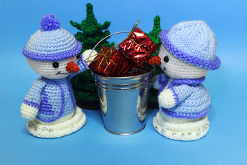 two snowmen near a bucket with gifts
