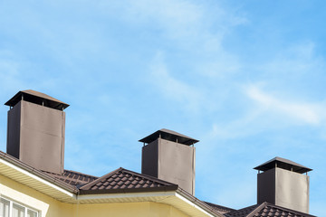 the roof of the house with pipes on background of blue sky