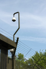 Obraz premium Camera and barbed wire fence surrounding a prison