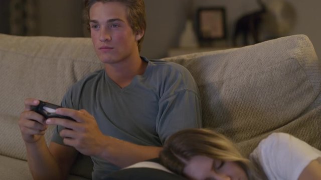 Close up shot of girl sleeping while boy plays video game / Cedar Hills, Utah, United States