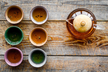 Set for tea ceremony. Glass teapot and ceramic cups on rustic wooden background top view