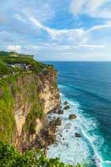 View of Uluwatu cliff with tourists, pavilion and blue sea in Bali, Indonesia