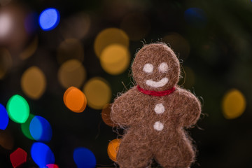 felted ginger bread man against christmas tree bokeh lights 