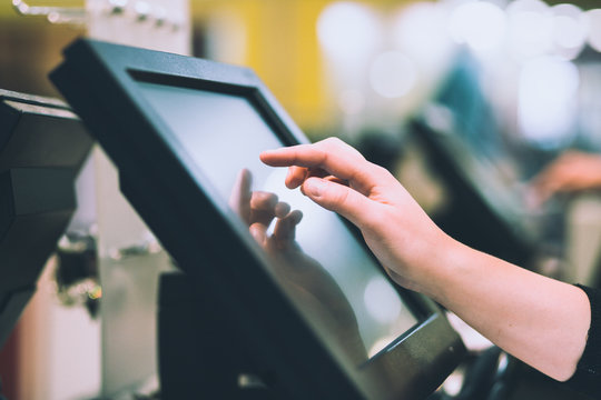 Young woman hand doing process payment on a touchscreen cash register, finance concept (color toned image)
