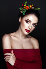 Naklejka premium Beautiful woman portrait with red and yellow berries on head and with black hair and red lips.