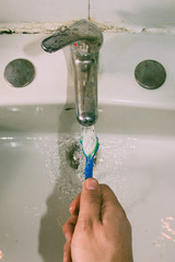 Cleaning the toothbrush under the water, self perspective