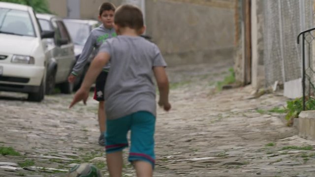 Medium slow motion panning shot of children playing street soccer / Veliko Tarnovo, Bulgaria