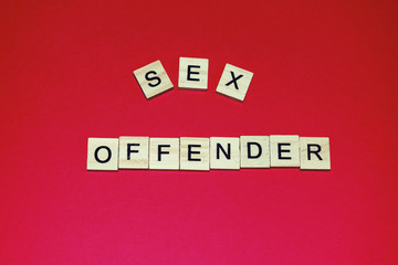 Wooden blocks on a pink background spelling words Sex Offender. Modern style