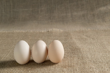 three chicken eggs on a linen burlap