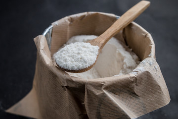 Wooden spoon with flour, close up. black background.