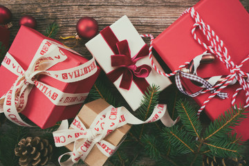 Christmas gift giving concept - christmas presents in red paper boxes with ribbons on wooden table , toned