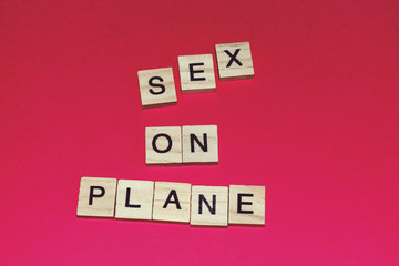 Wooden blocks on a red background spelling words Sex On Plane