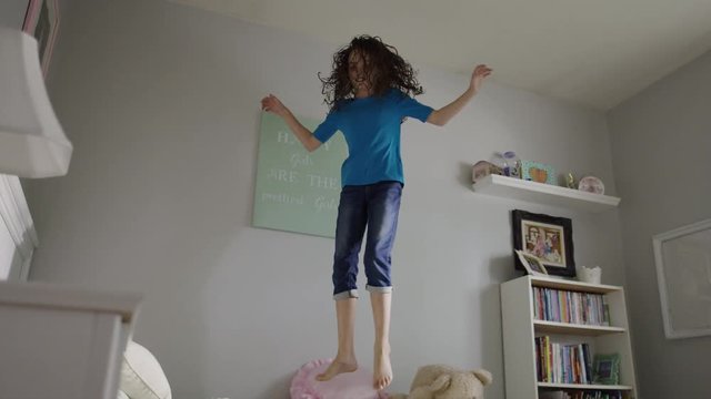 Medium slow motion panning shot of girl jumping on bed / Provo, Utah, United States