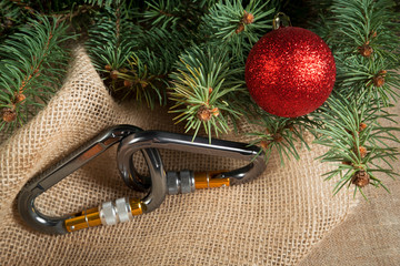 carabiners for climbing on Christmas tree with red ball, a festive sports abstraction on linen burlap