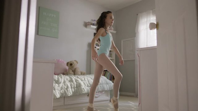 Medium slow motion shot of girl practicing ballet in bedroom / Provo, Utah, United States