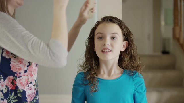 Close up panning shot of mother measuring height of daughter on wall / Provo, Utah, United States