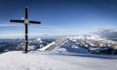 Fototapeta na wymiar Gipfelkreuz mit Berge im Hintergrund im Winter