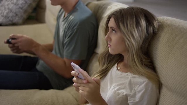 Medium high angle shot of girl irritated at boy playing video game / Cedar Hills, Utah, United States