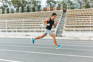 Fototapeta premium Young athletic man running on the stadium in the morning