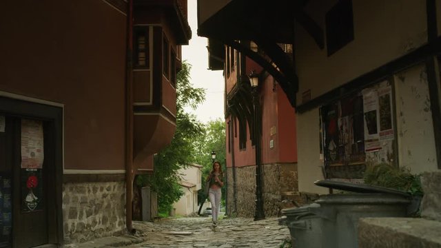 Wide shot of woman walking and photographing architecture / Plovdiv, Bulgaria