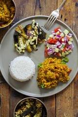 Indian meal with masoor dal - lentil curry, dahi baingan, rice and salad