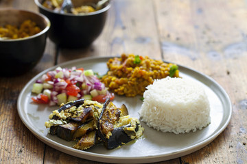 Indian meal with masoor dal - lentil curry, dahi baingan, rice and salad