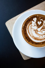 Cup of hot latte art coffee on black table
