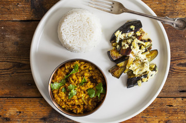 Indian meal with masoor dal - lentil curry, dahi baingan, rice and salad