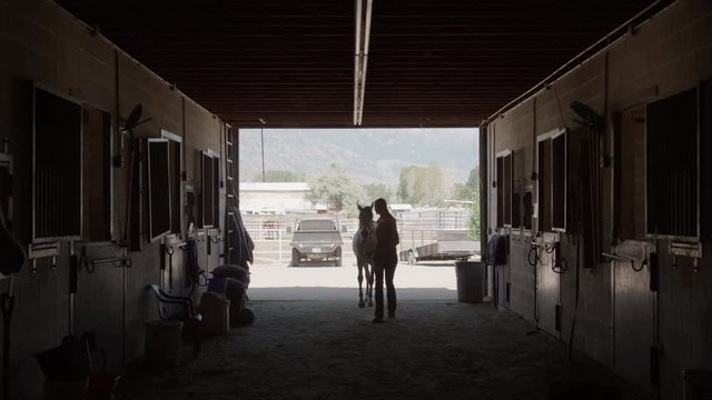 Wide slow motion shot of girl leading horse into stable / Lehi, Utah, United States