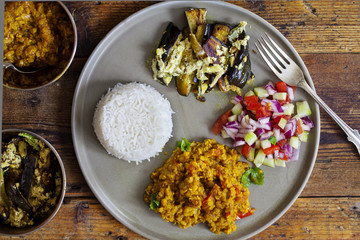 Indian meal with masoor dal - lentil curry, dahi baingan, rice and salad
