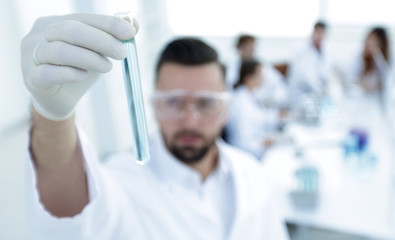 image is blurred. young scientist holding tube with the reagents
