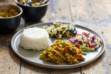 Indian meal with masoor dal - lentil curry, dahi baingan, rice and salad