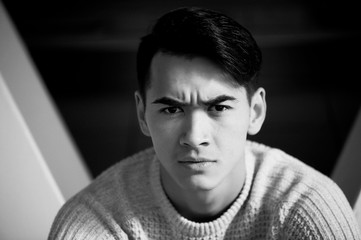 Obraz premium A young man with dark hair and eyes frowns. Reverie