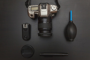 top view of work space photographer with dslr camera system, camera cleaning kit and camera accessory on black table background