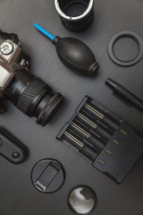 top view of work space photographer with dslr camera system, camera cleaning kit and camera accessory on black table background