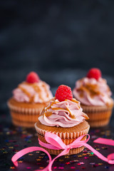 Raspberry and caramel cupcakes on dark background