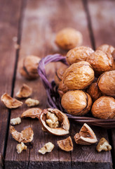 Whole walnuts in basket on rustic old wooden table