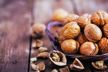 Whole walnuts in basket on rustic old wooden table